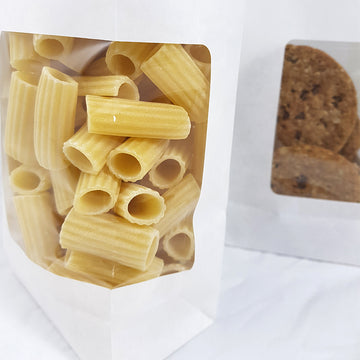 Dettaglio di buste sacchetti bianchi con finestra, pieni di pasta e biscotti